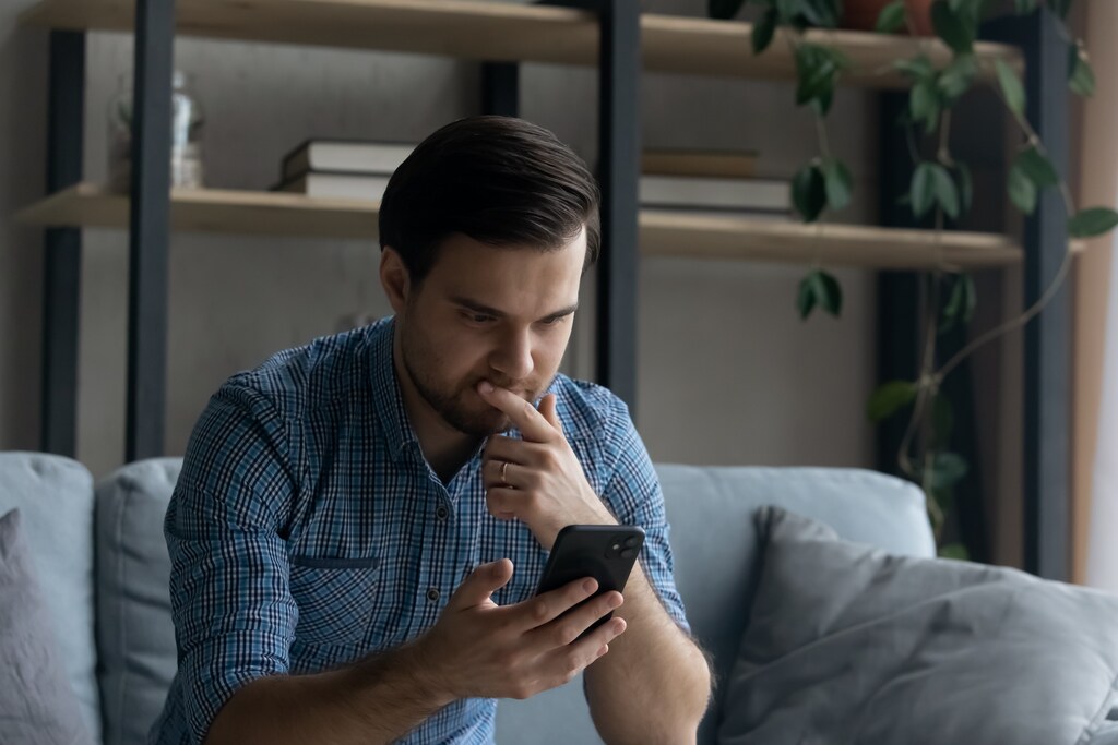 homem pesquisando no celular como sair das dívidas ganhando pouco