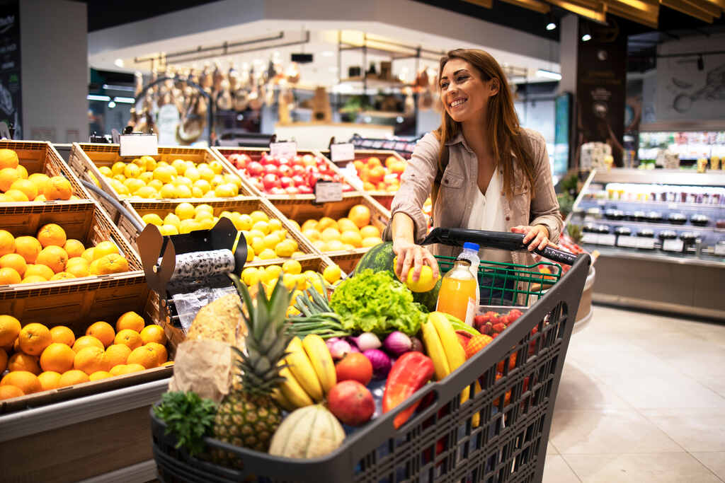 mulher em supermercado com carrinho cheio de itens da sua lista de compra do mês