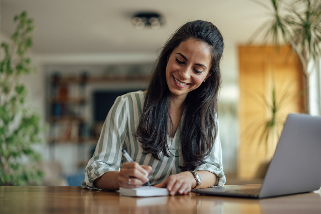 mulher fazendo anotações representando como organizar as finanças