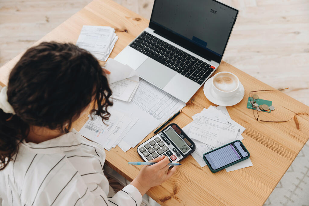 pessoa em escritório com computador e calculadora para organizar as finanças para autônomos