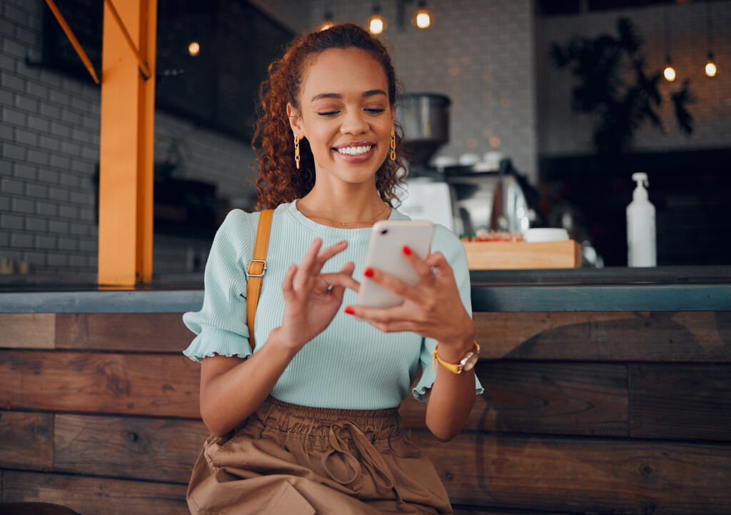 mulher usando celular para realizar a sua gestão financeira pessoal