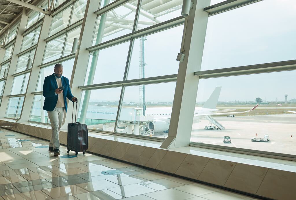 homem com mala em aeroporto, pronto para viajar com seu cartão para milhas