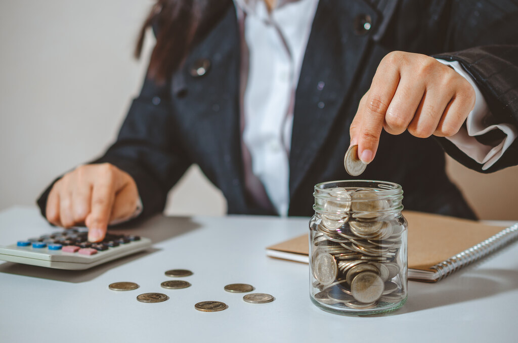 pessoa adicionando moedas em recipiente, representando a organização financeira pessoal