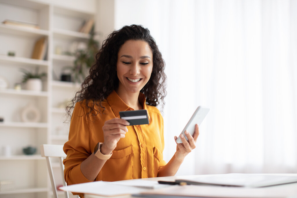 mulher fazendo compra pelo celular usando seu cartão de crédito para negativado