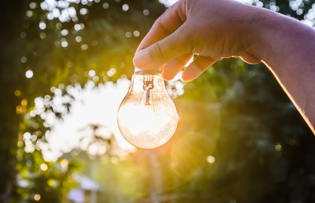 pessoa segurando lâmpada acesa, representando quanto custa colocar energia solar