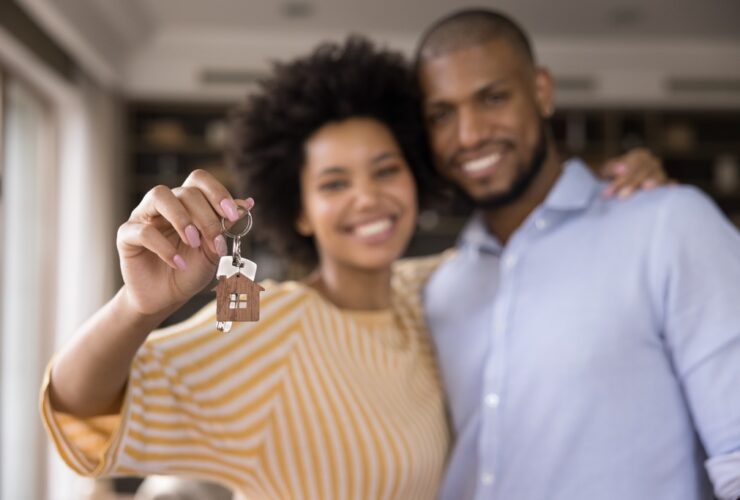 Casal com chave da casa na mão depois de entender quanto guardar por mês para comprar uma casa