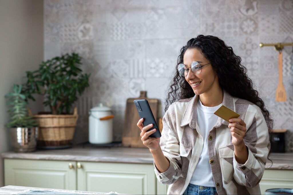 investidora fazendo aplicações pelo celular após saber sobre os tipos de investidores