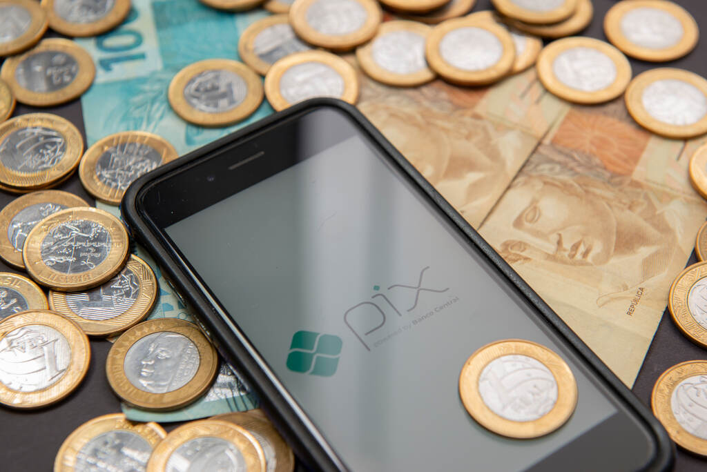 Moedas e celular com pix por aproximação